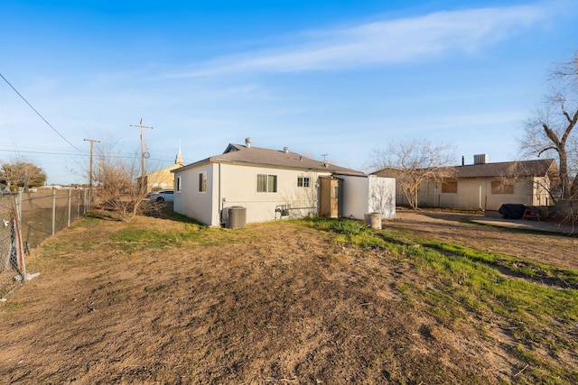 rear view of house featuring stucco siding, cooling unit, and fence