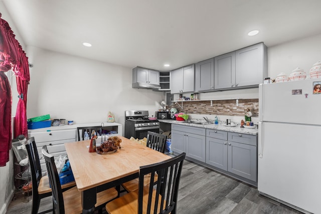 kitchen with a sink, stainless steel range with gas cooktop, freestanding refrigerator, and gray cabinetry