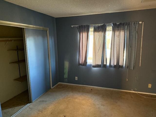 unfurnished bedroom with carpet, a textured ceiling, and a closet