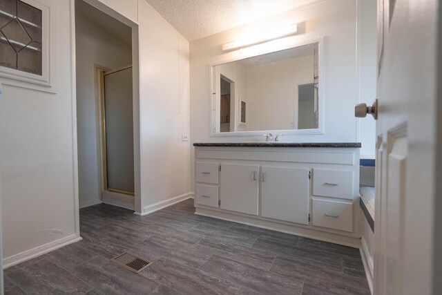 bathroom featuring hardwood / wood-style flooring, vanity, a textured ceiling, and walk in shower