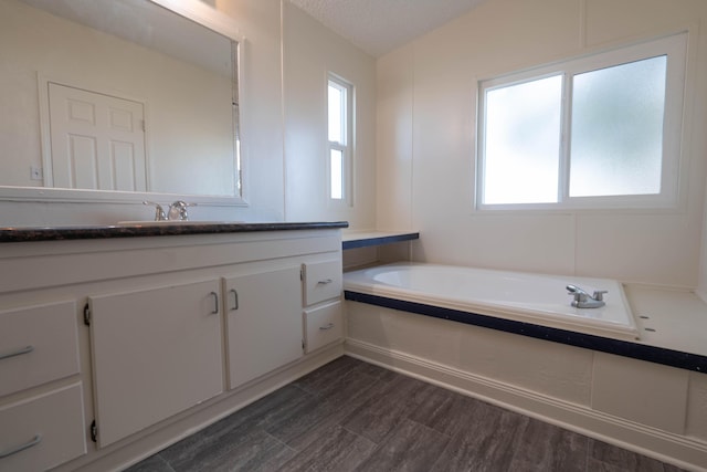 bathroom featuring vanity, a bath, vaulted ceiling, hardwood / wood-style flooring, and a textured ceiling