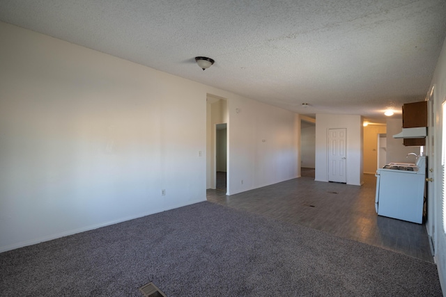 unfurnished living room with a textured ceiling, washer / clothes dryer, and dark carpet