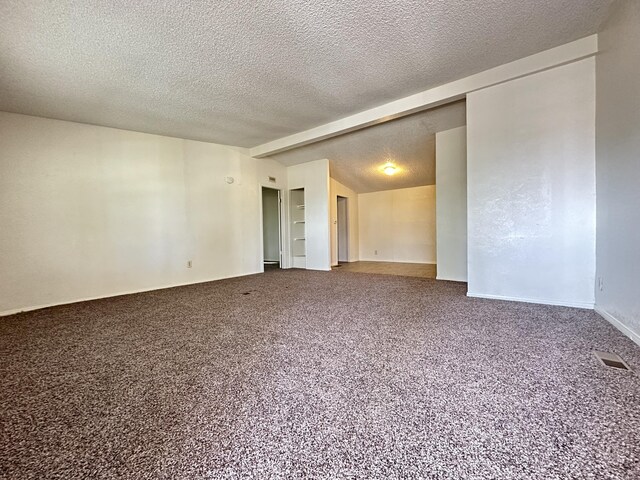 carpeted empty room featuring vaulted ceiling with beams and a textured ceiling