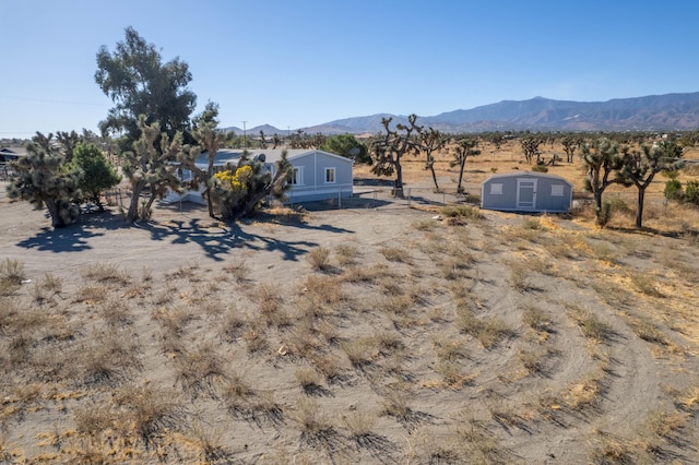 view of yard featuring a mountain view, a storage unit, and a rural view