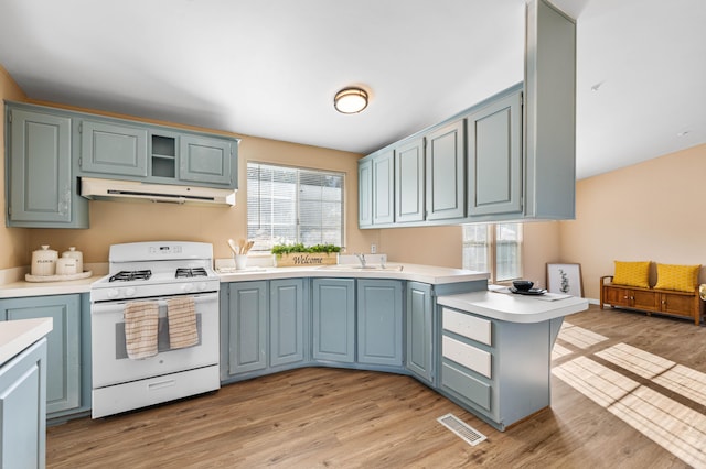 kitchen featuring sink, light hardwood / wood-style floors, kitchen peninsula, and white gas stove