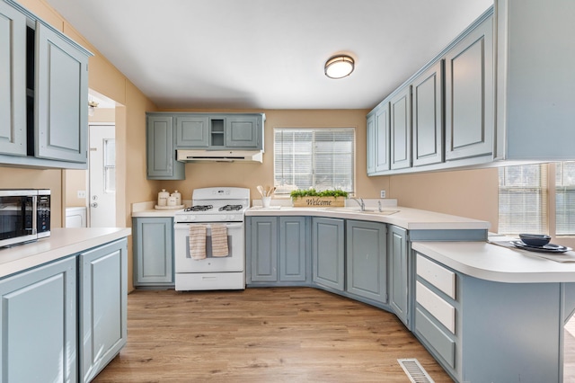 kitchen with kitchen peninsula, sink, gas range gas stove, and light wood-type flooring