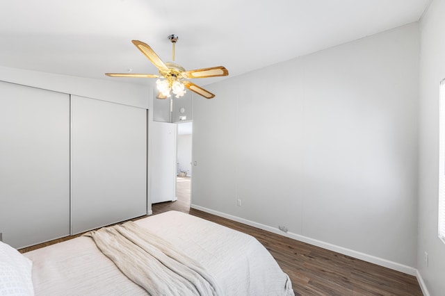 bedroom with dark wood-type flooring, ceiling fan, and a closet