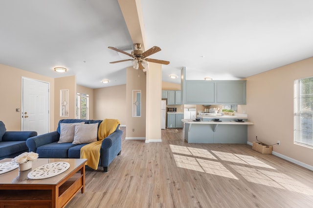 living room with ceiling fan, light hardwood / wood-style flooring, and vaulted ceiling with beams