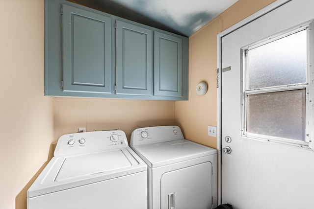 clothes washing area featuring cabinets and separate washer and dryer