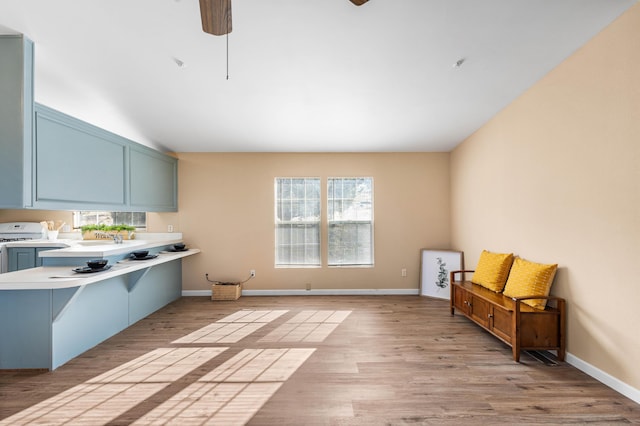 kitchen with a breakfast bar, ceiling fan, light hardwood / wood-style floors, vaulted ceiling, and kitchen peninsula