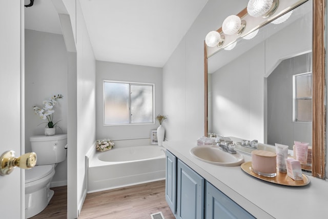 bathroom with hardwood / wood-style flooring, vanity, a tub to relax in, and toilet