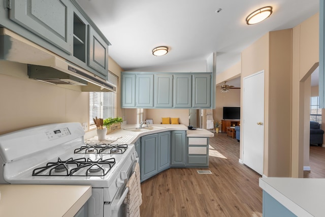 kitchen featuring a healthy amount of sunlight, vaulted ceiling, white range with gas stovetop, and light wood-type flooring