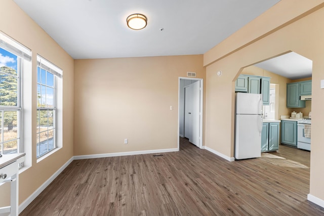 interior space featuring hardwood / wood-style flooring, vaulted ceiling, green cabinets, and white appliances