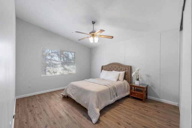 bedroom with ceiling fan, lofted ceiling, and wood-type flooring