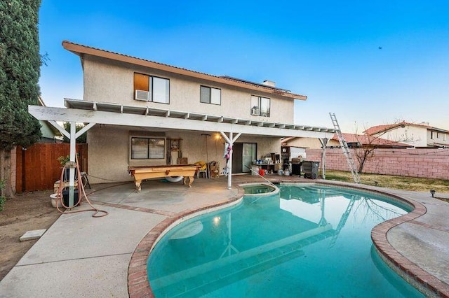 rear view of property with a patio area and a pool with hot tub