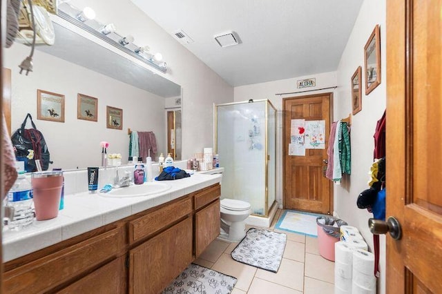 bathroom featuring tile patterned floors, vanity, a shower with shower door, and toilet