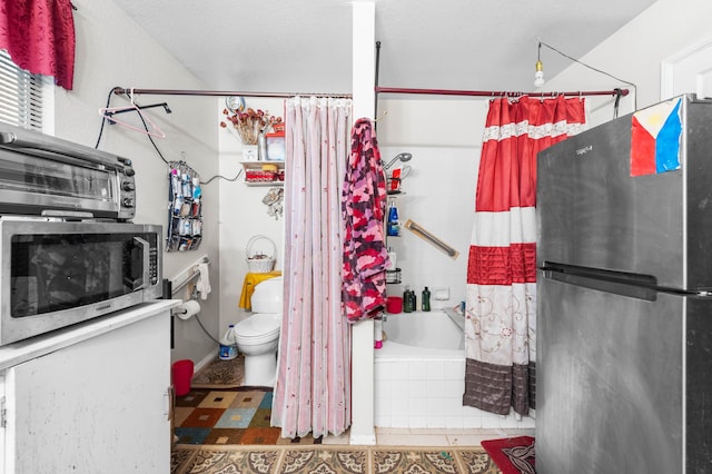 bathroom featuring tile patterned flooring, shower / tub combo, and toilet