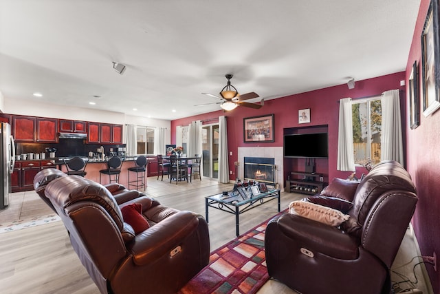 living room featuring ceiling fan, a fireplace, and light hardwood / wood-style floors