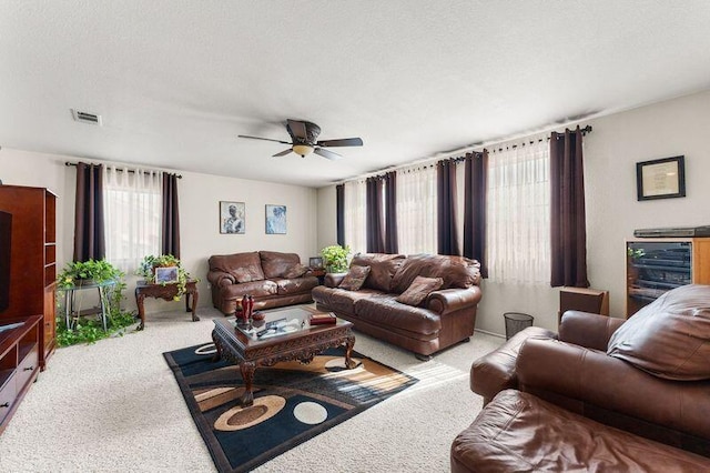 living room featuring light carpet, a textured ceiling, and ceiling fan