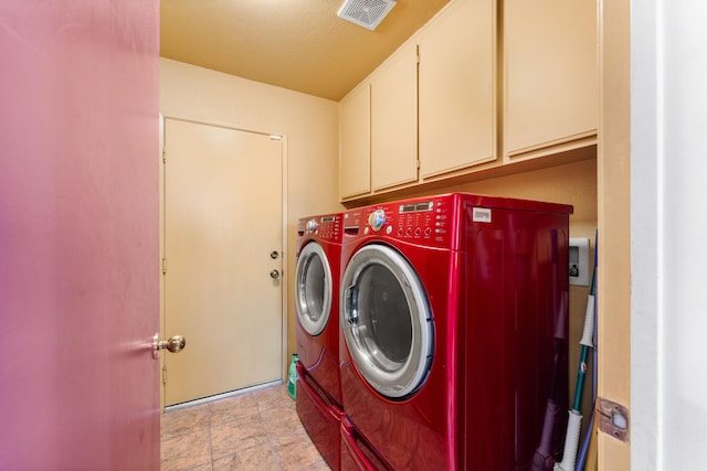 clothes washing area featuring washer and clothes dryer and cabinets