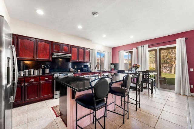 kitchen featuring appliances with stainless steel finishes, backsplash, a kitchen breakfast bar, sink, and an island with sink