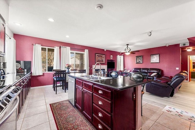 kitchen featuring ceiling fan, sink, a center island with sink, light tile patterned floors, and appliances with stainless steel finishes