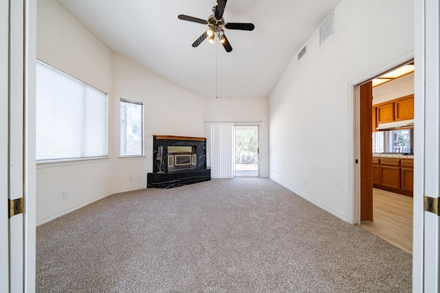 unfurnished living room featuring a tile fireplace, ceiling fan, light colored carpet, and lofted ceiling