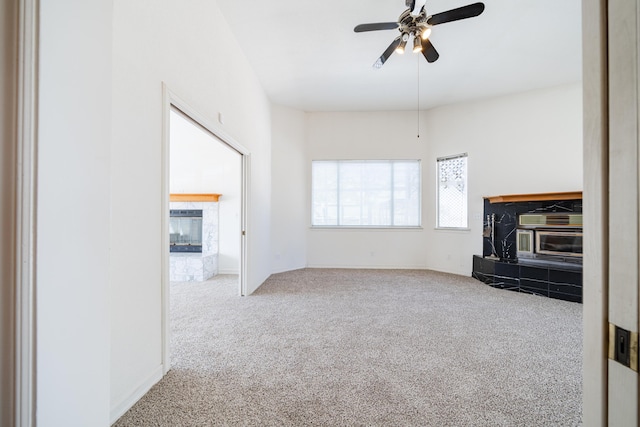 unfurnished living room featuring a tiled fireplace, light carpet, and ceiling fan