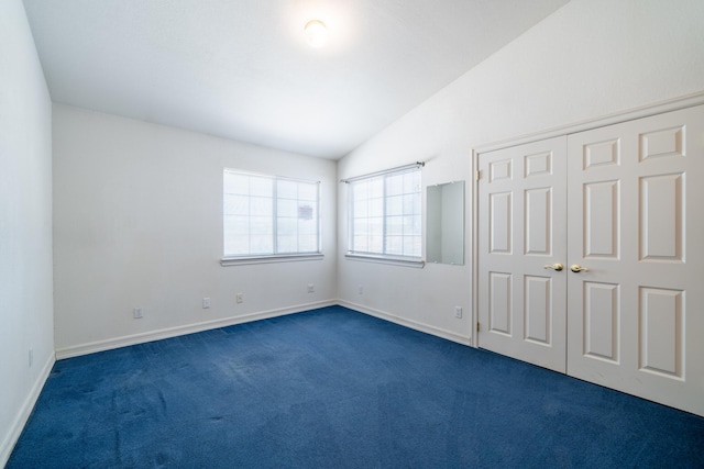 unfurnished bedroom featuring a closet, dark carpet, and lofted ceiling