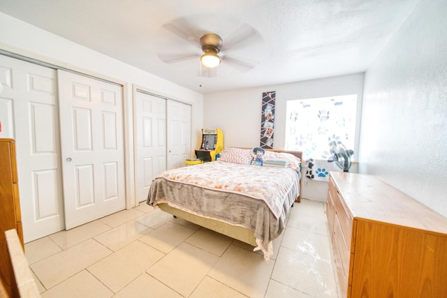 bedroom featuring a ceiling fan, two closets, and light tile patterned floors