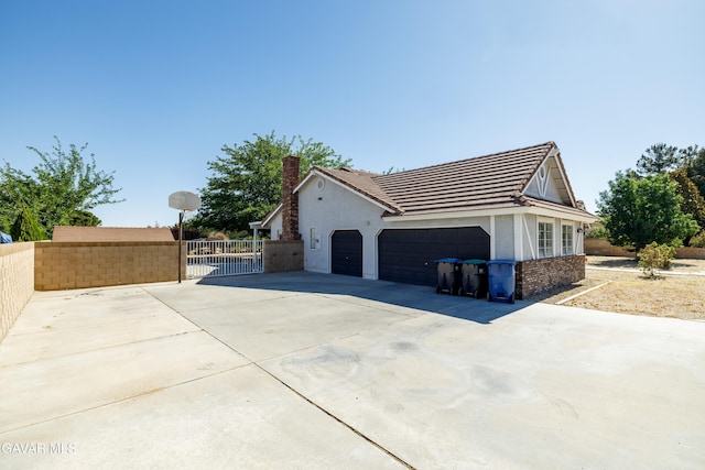 3807 Paula Ln, Lancaster, CA 93535 - view of side of property with an attached garage, stucco siding, driveway, a chimney, and a tile roof
