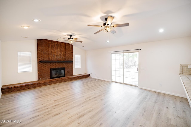 3807 Paula Ln, Lancaster, CA 93535 - unfurnished living room with vaulted ceiling, ceiling fan, a fireplace, and light wood-type flooring