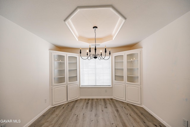 3807 Paula Ln, Lancaster, CA 93535 - unfurnished dining area with a chandelier, light wood-style floors, and a raised ceiling
