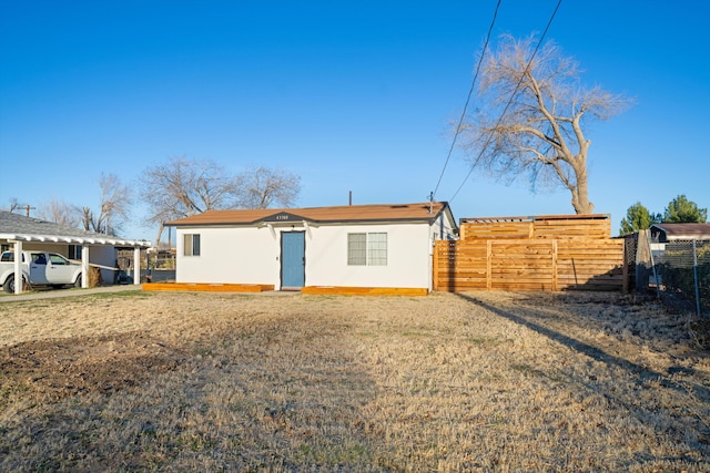 back of property featuring fence and stucco siding