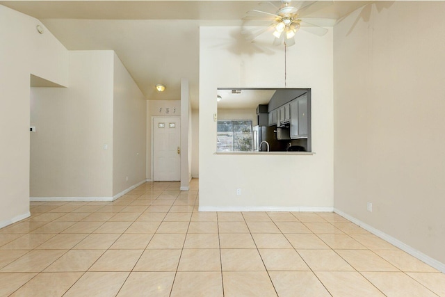 empty room with ceiling fan, light tile patterned floors, and vaulted ceiling