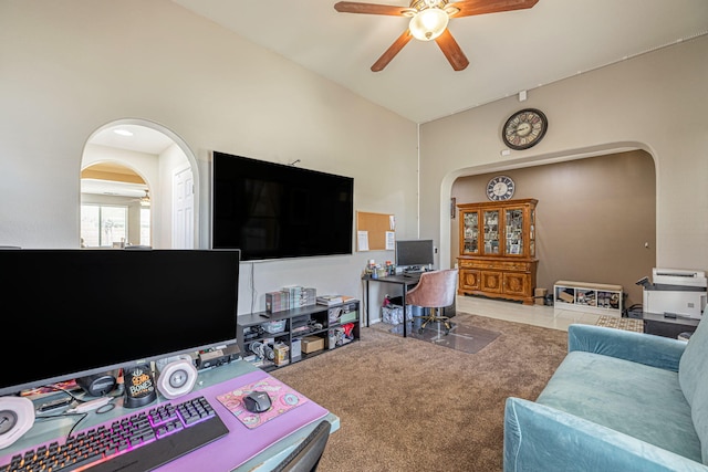 living area featuring arched walkways, ceiling fan, vaulted ceiling, and carpet