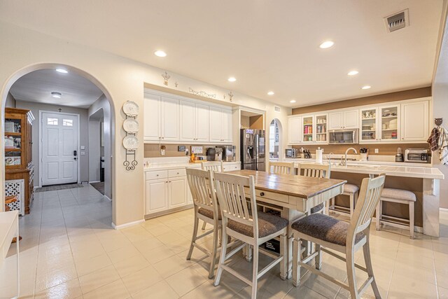 dining space featuring arched walkways, recessed lighting, light tile patterned floors, and baseboards