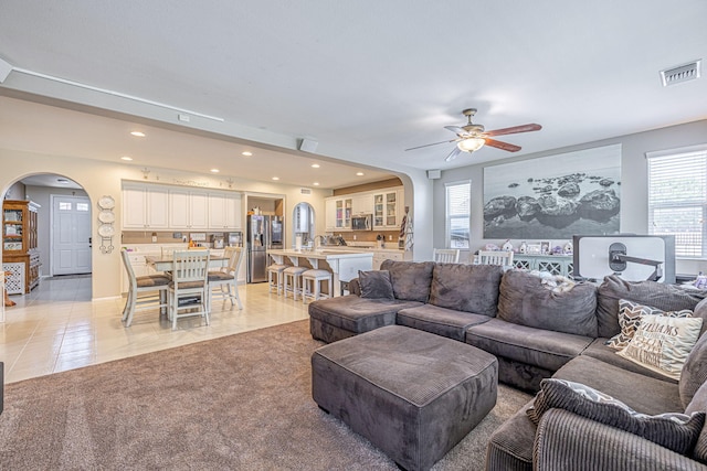 living area featuring arched walkways, a ceiling fan, recessed lighting, and light tile patterned floors