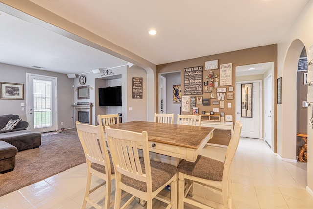 dining space with light carpet, arched walkways, recessed lighting, baseboards, and light tile patterned floors