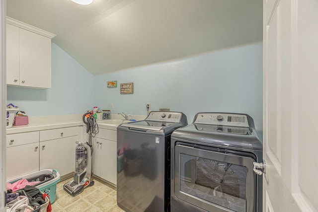 clothes washing area featuring separate washer and dryer and cabinet space