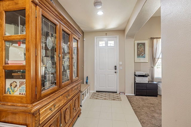 entryway featuring baseboards, light colored carpet, and light tile patterned floors