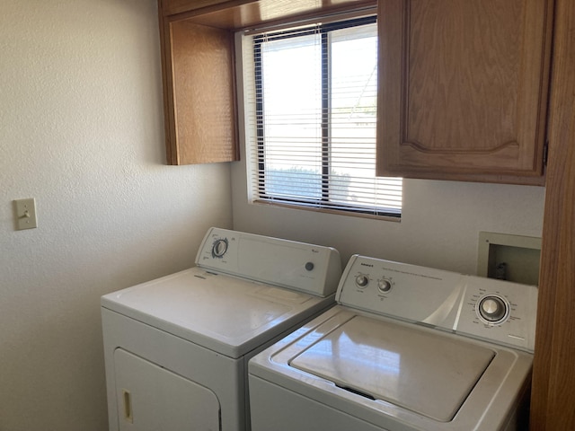 washroom featuring cabinets and washer and clothes dryer