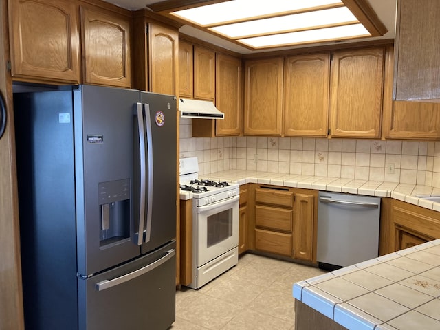 kitchen featuring decorative backsplash, stainless steel appliances, and tile counters