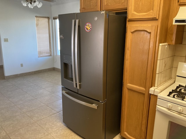 kitchen featuring light tile patterned flooring, stainless steel fridge, ceiling fan, and white range with gas stovetop