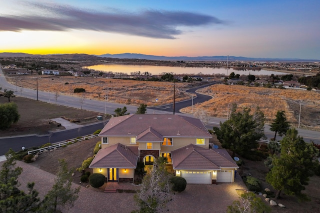 aerial view at dusk featuring a water and mountain view