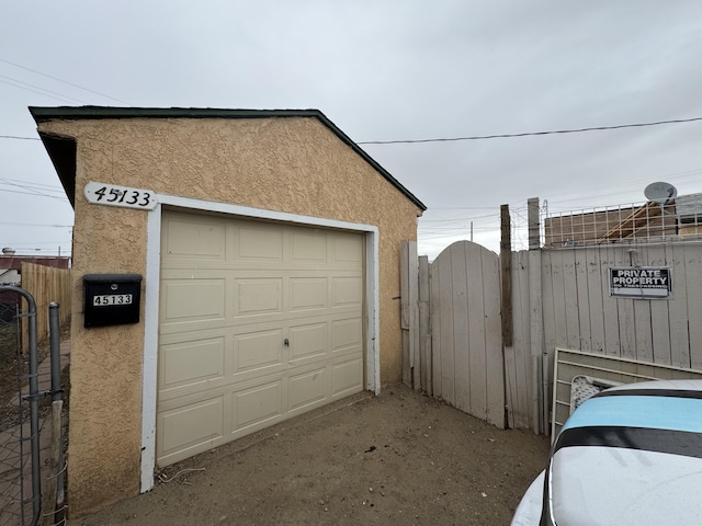 detached garage with a gate and fence