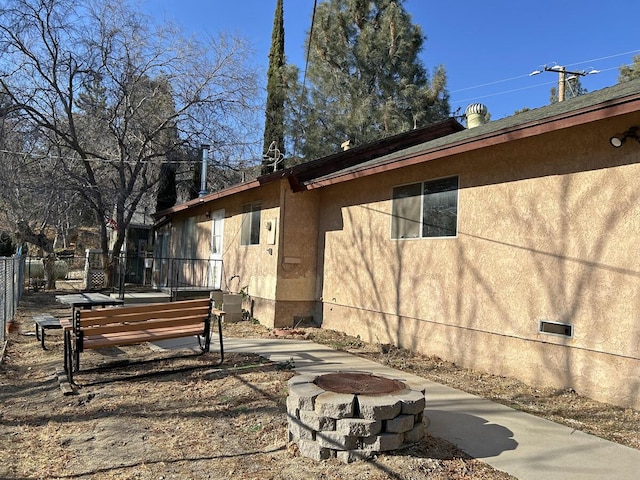 view of side of property with a patio area and a fire pit