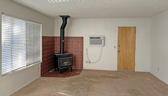 living room featuring carpet, a wood stove, a textured ceiling, and a wall unit AC