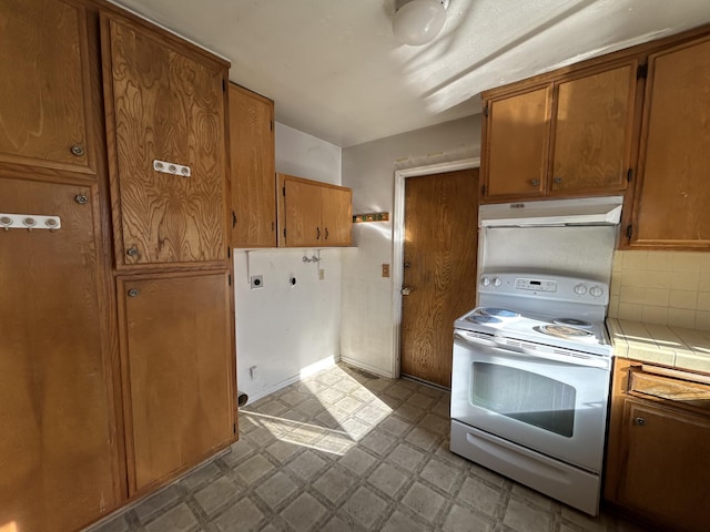 kitchen with tile counters, decorative backsplash, and electric stove