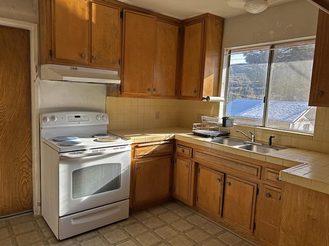 kitchen with sink, backsplash, tile counters, and white electric stove